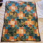 Simple quilted project made out of squares -- yellow, orange, teal, green and gold
